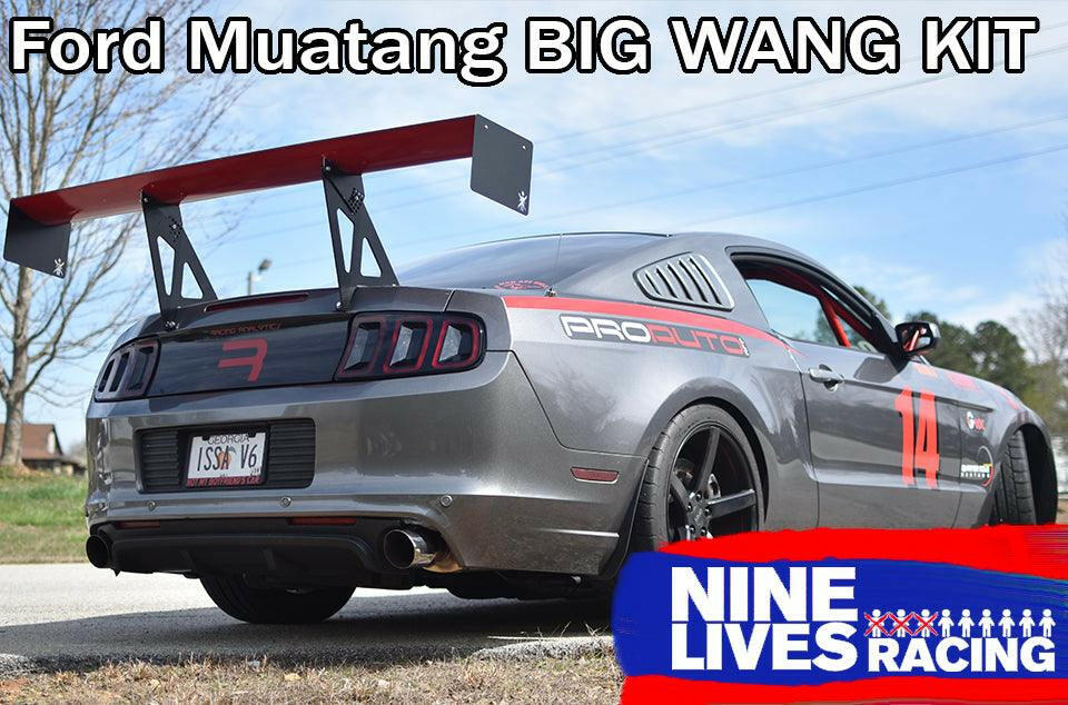 A grey Ford Mustang with a large rear wing and race decals, including the number 14, is parked outdoors. A banner at the top reads "Mustang Big Wang Kit '10-14 S197 II," and the bottom right has a "9livesracing" logo.