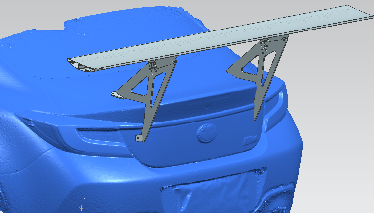 A digital rendering of a blue car's rear end displays a large, elevated rear wing spoiler from the 9livesracing GR86 / BRZ Wang Kit '22+. The sleek design features extruded aluminum wings with metallic mounting brackets, expertly positioned on the trunk lid to optimize performance airfoils. The car's license plate is not visible.