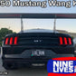 Rear view of a black GT Mustang equipped with a large Mustang Big Wang Kit '14+ S550 from 9livesracing, enhancing Mustang performance with its impressive down-force. A license plate reads "LOL RUN." The car is parked next to other vehicles. The image includes text: "S550 Mustang Wang Kits," "Available in 74"" and "Nine Lives Racing" with the brand's logo.